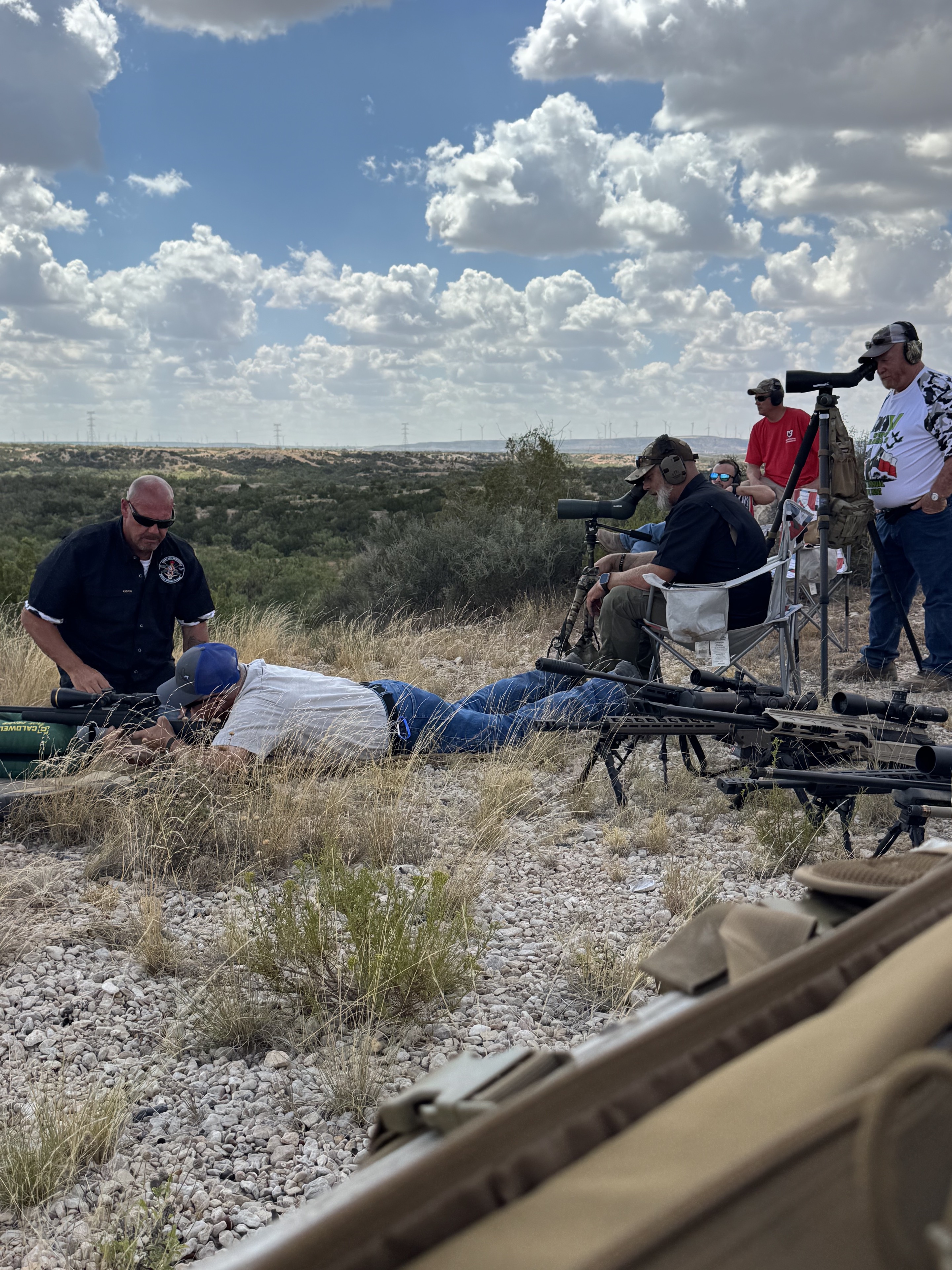 Veterans working together at a long-range shooting position under a wide Texas sky