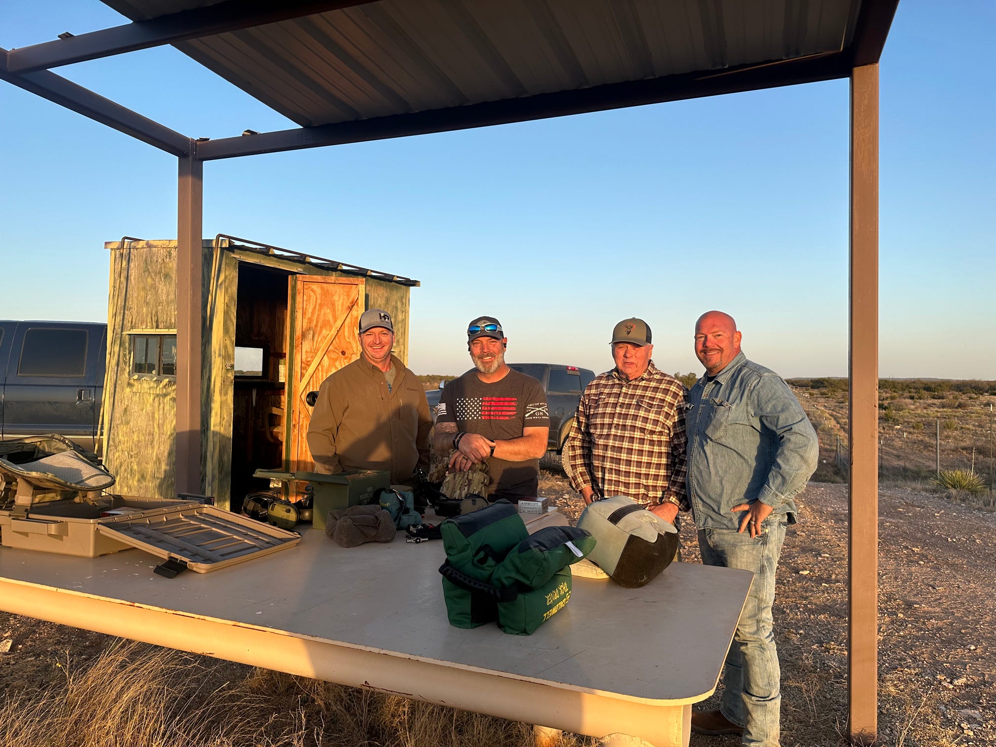 Four veterans gathered around the range bench in the evening light