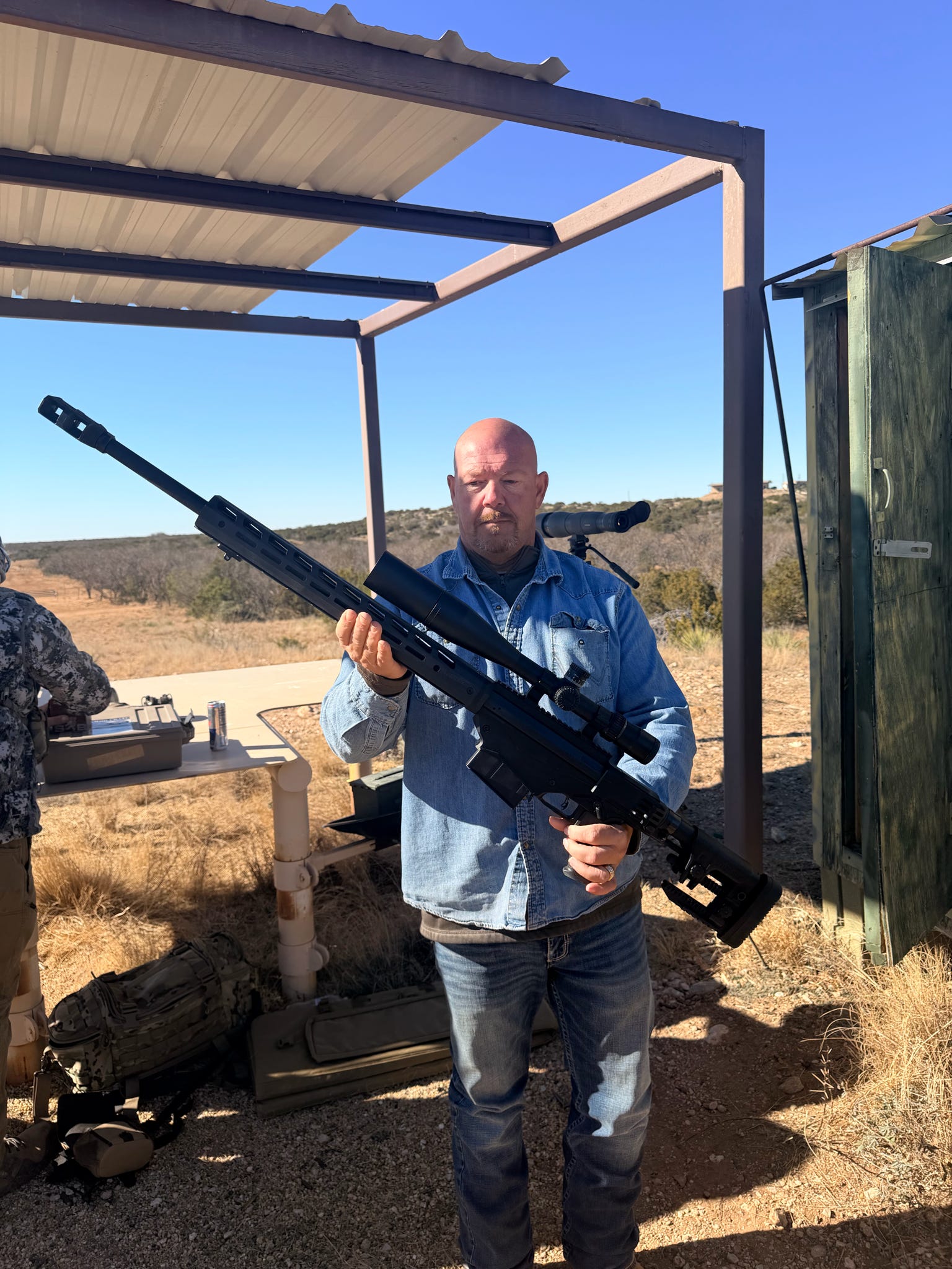 A veteran preparing a precision rifle beside the range shelter