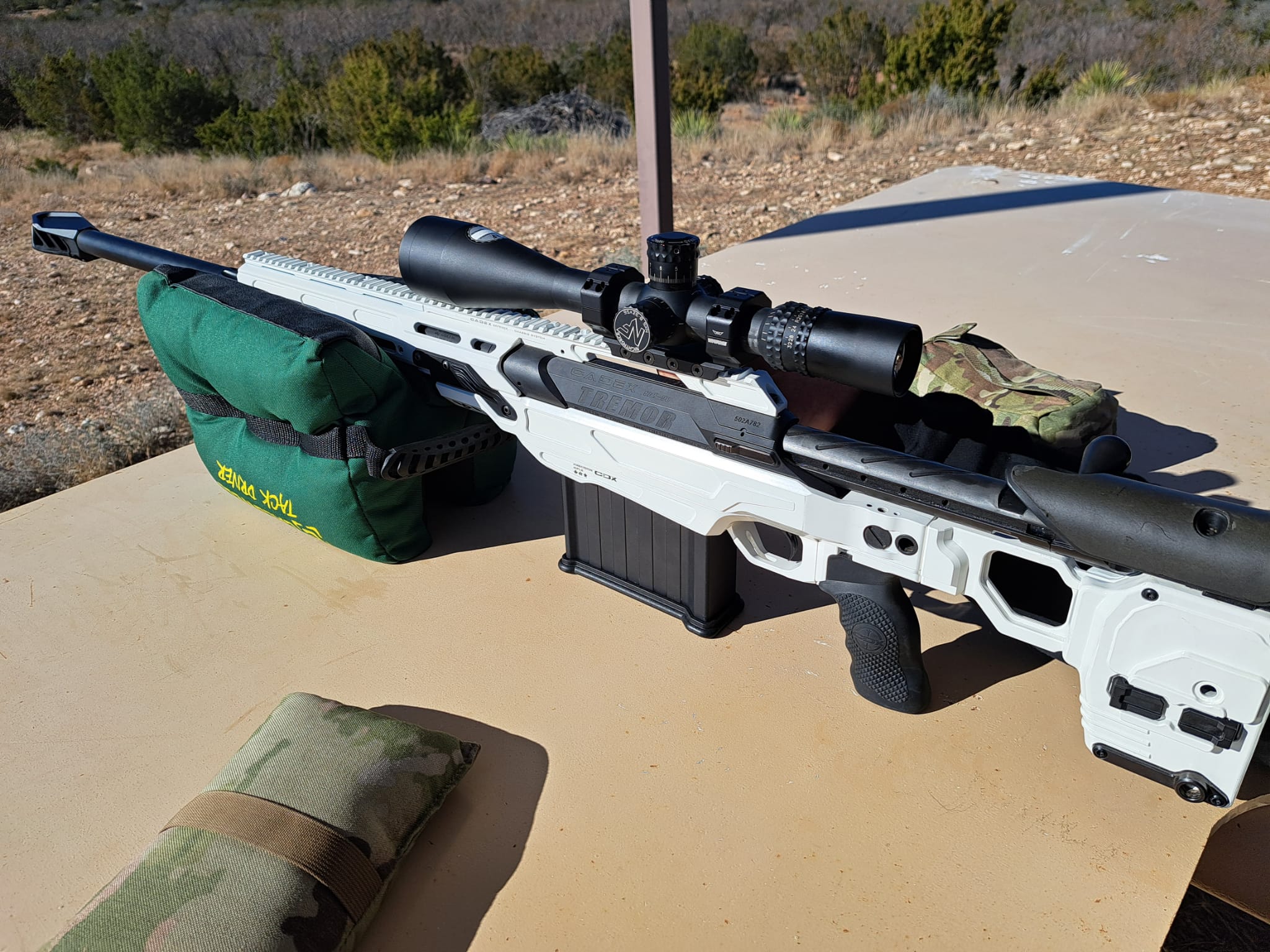 A white precision rifle resting on bags at the bench